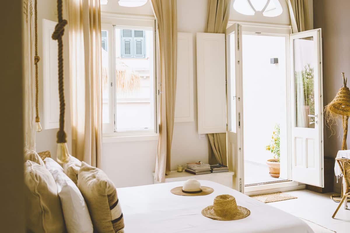 Een slaapkamer met een bed, gordijnen, een raam en een deur.