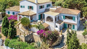 A white villa with multiple levels, green shutters, and a stone staircase. - Cavall Bernat 14 - Majorca Villa by the beach (Cala Sant Vicenç)