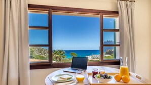 A breakfast setup with a laptop, a glass of orange juice, a bowl of fruit, and a tray with a bottle of juice and a bowl of olives. - Cavall Bernat 14 - Majorca Villa by the beach (Cala Sant Vicenç)