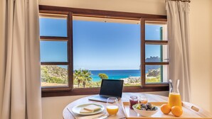 A breakfast table with a laptop, a glass of orange juice, a bowl of fruit, and a tray with a bottle of juice and a cutting board. - Cavall Bernat - Villa by the sea Majorca (Cala Sant Vicenç)