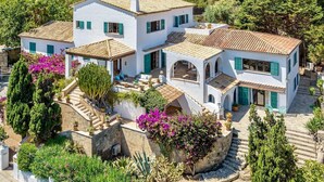 A white villa with multiple levels, green shutters, and a stone staircase. - Cavall Bernat - Villa by the sea Majorca (Cala Sant Vicenç)