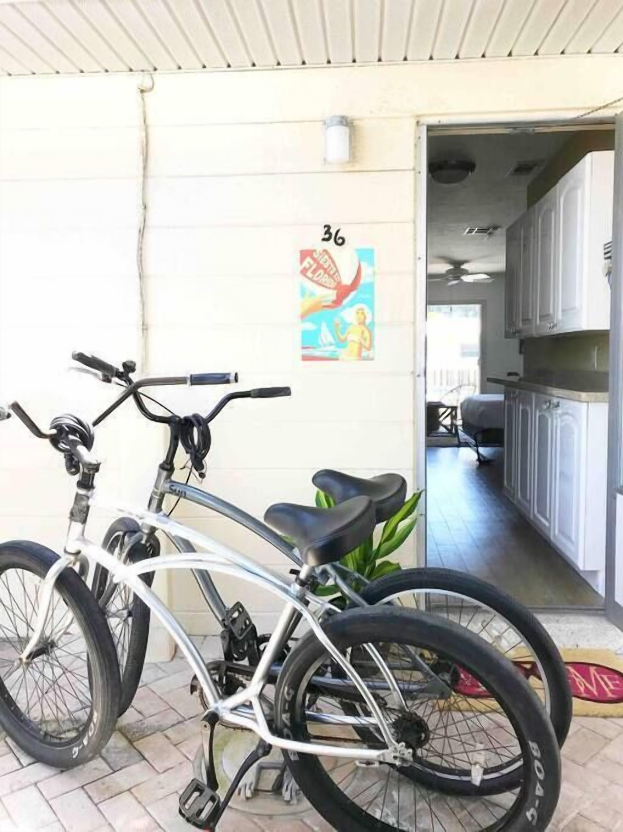 A bicycle parked outside a building with a tiled floor and a door leading to a hallway.