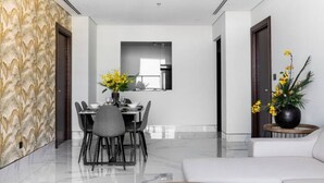 Un comedor moderno con suelo de mármol, una mesa de comedor con sillas y un jarrón con flores amarillas.