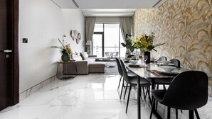 Un comedor moderno con piso de mármol, una mesa para cuatro comensales y un sofá al fondo.