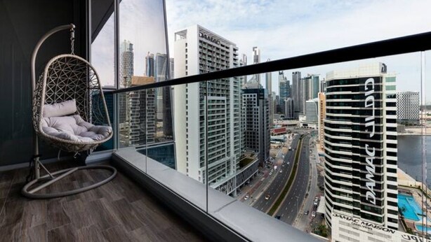 Una habitación moderna con un ventanal grande, un sillón colgante y vistas a la ciudad.