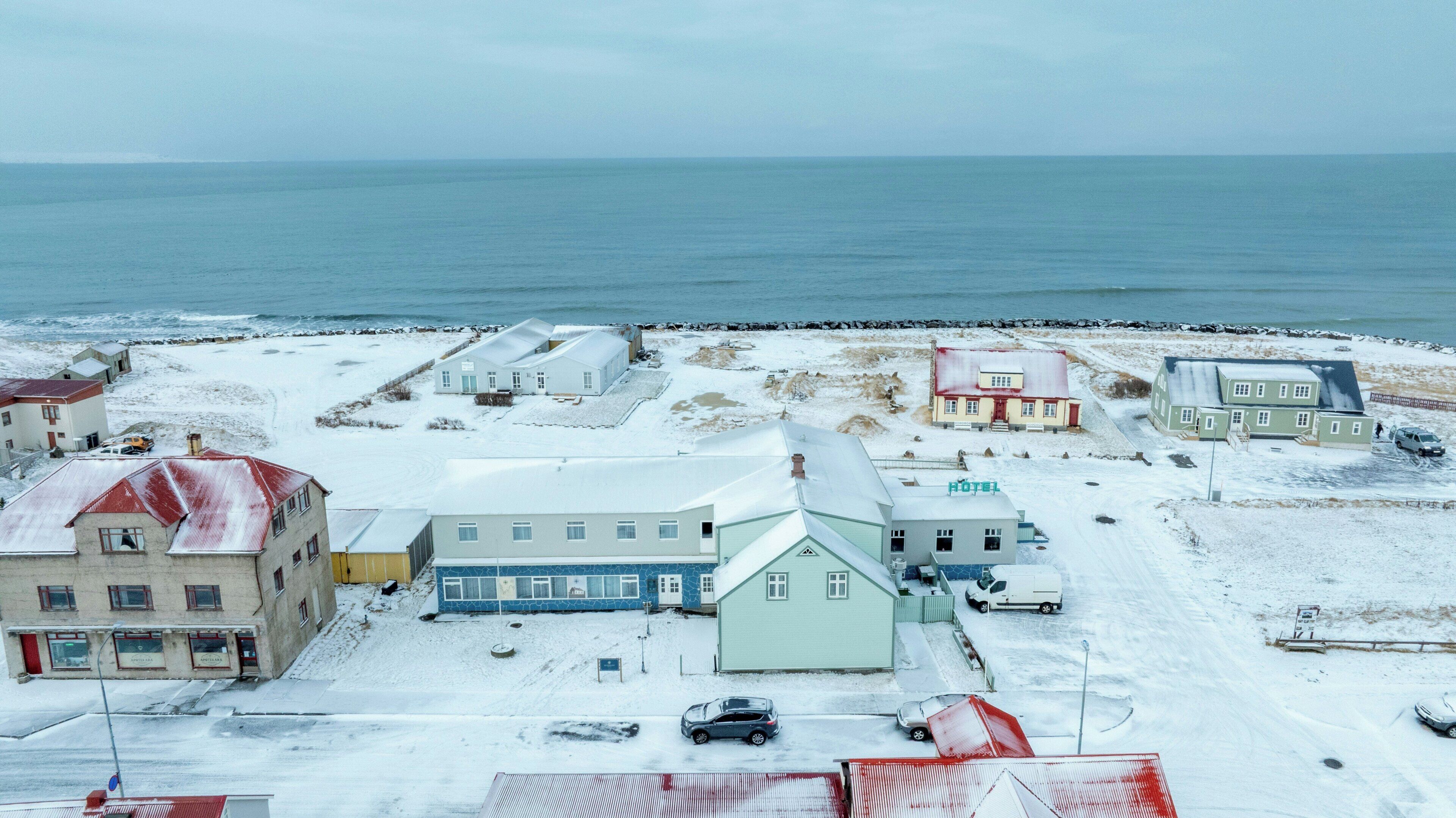 A hotel with a snow-covered parking area and a view of the sea.