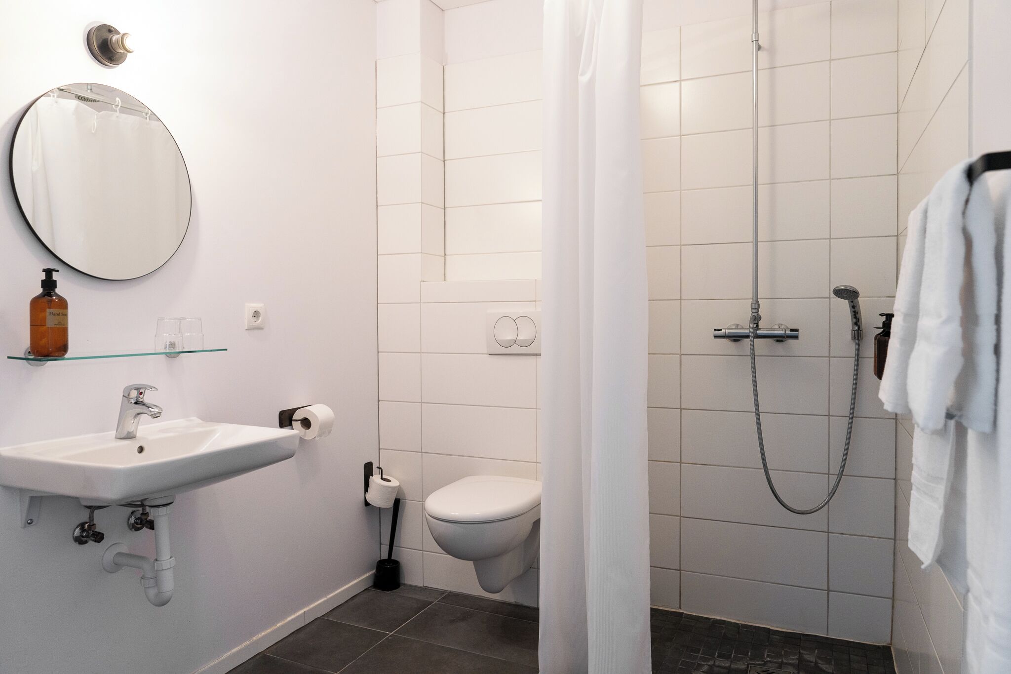Un baño con lavamanos, inodoro, ducha y espejo.