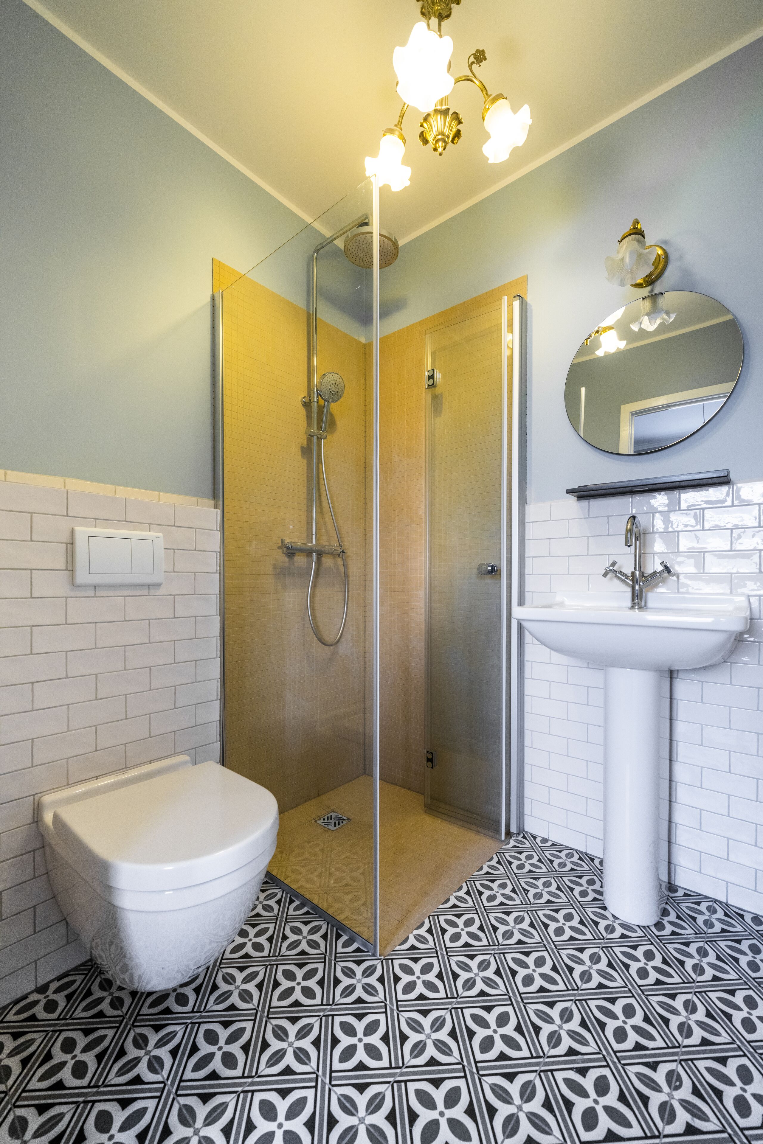 Un baño con inodoro, ducha, lavabo y espejo.