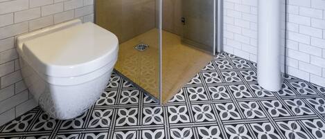 Un baño con inodoro, ducha, lavabo y espejo.
