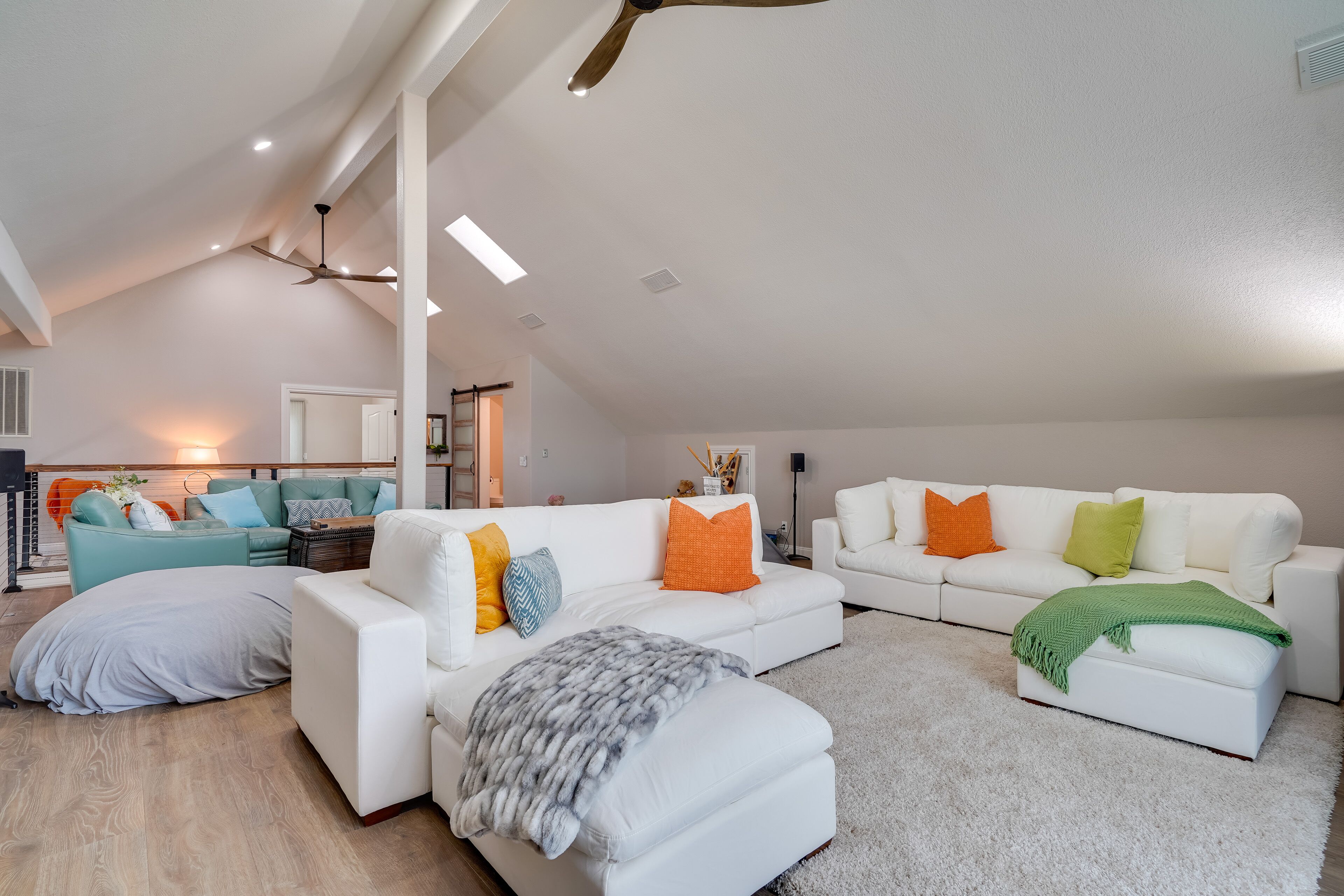 A spacious living area with a high ceiling, white sofas, and a variety of throw pillows.