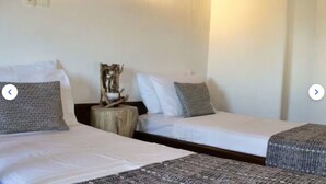 Ett hotellrum med två separata sängar, ett nattduksbord med en lampa och en prydnadsväxt.