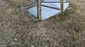 A wooden boardwalk leading to a beach with a view of the ocean and distant shoreline.
