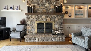 A cozy living room with a stone fireplace, wooden beams, and nautical-themed decor.