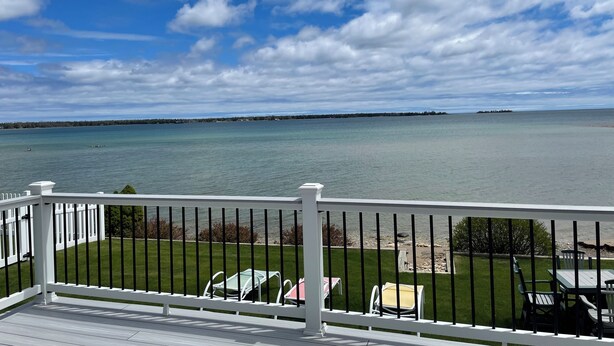 A deck with a view of a calm body of water and a distant shoreline.