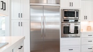 A modern kitchen with white cabinetry, a stainless steel refrigerator, a microwave, and an oven. - Villa Paloma::Private escape with Pool & Hottub (Oceanside)