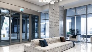 Eine moderne Lobby mit einer gepolsterten Couch, großen Fenstern und einer Marmorsäule.
