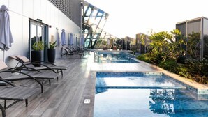 Ein moderner Poolbereich im Freien mit Liegestühlen und einem überdachten Pool.