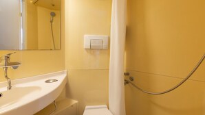 Baño con lavamanos, espejo, ducha e interruptor de luz en la pared.