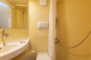 Baño con lavamanos, espejo, ducha e interruptor de luz en la pared.