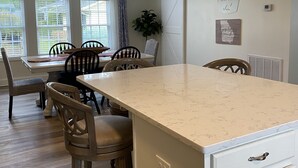 A modern kitchen with a large island, wooden chairs, and a dining table. - Lake Sinclair retreat with Boat Dock, Waterslide and BIG Views! (Milledgeville)