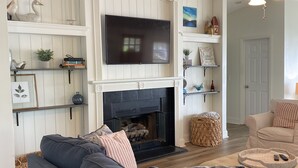 A living room with a fireplace, a television, and a ceiling fan. - Lake Sinclair retreat with Boat Dock, Waterslide and BIG Views! (Milledgeville)