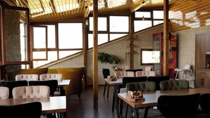 A restaurant with high ceilings, large windows, and a variety of seating options including booths and tables. - Cappadocia Panda Garden House (Nevsehir)