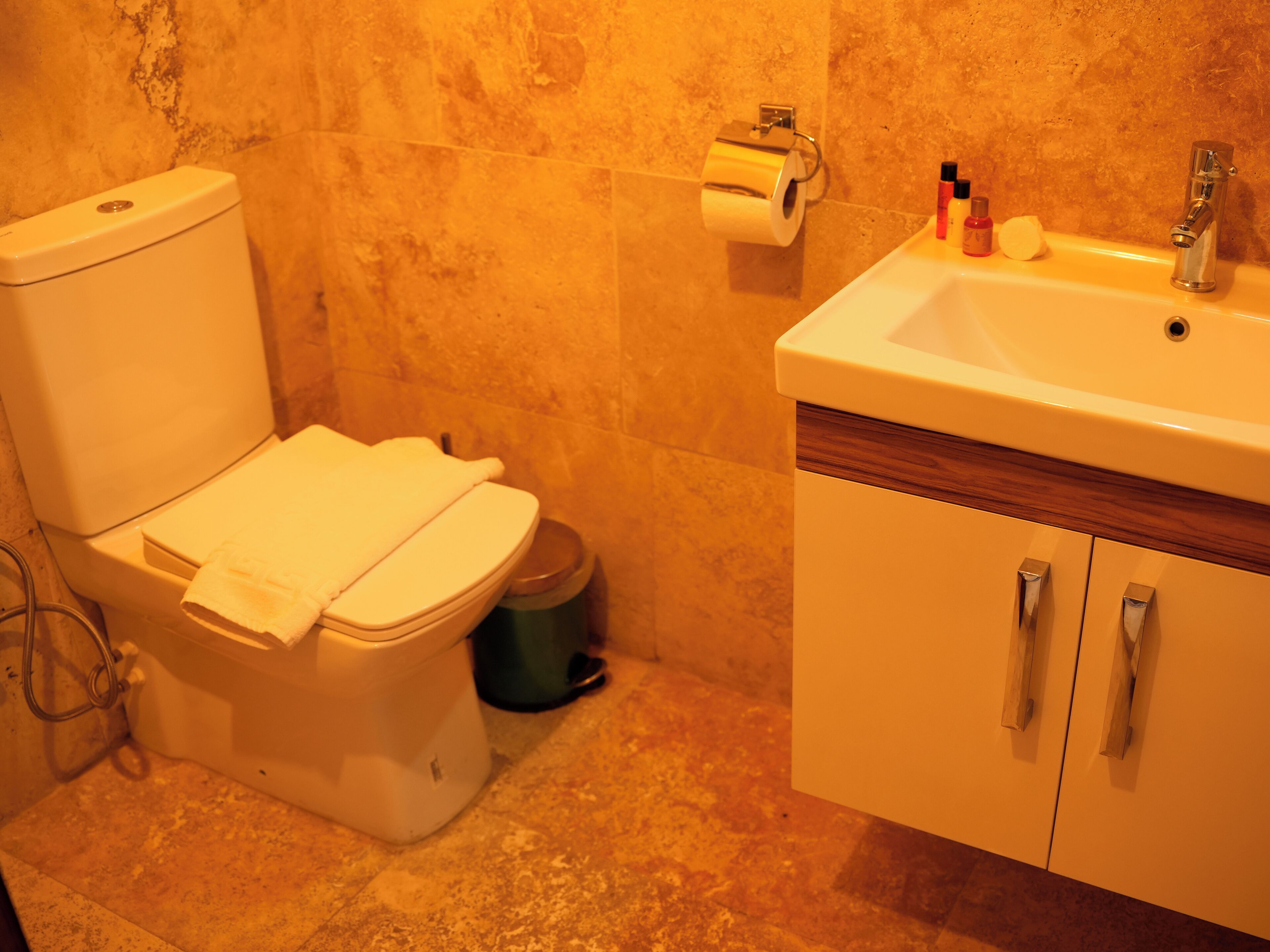 Un baño con inodoro, lavamanos y cubo de basura.