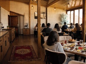 A restaurant with wooden interiors, a red rug, and patrons dining. - Panda Garden House (Nevsehir)