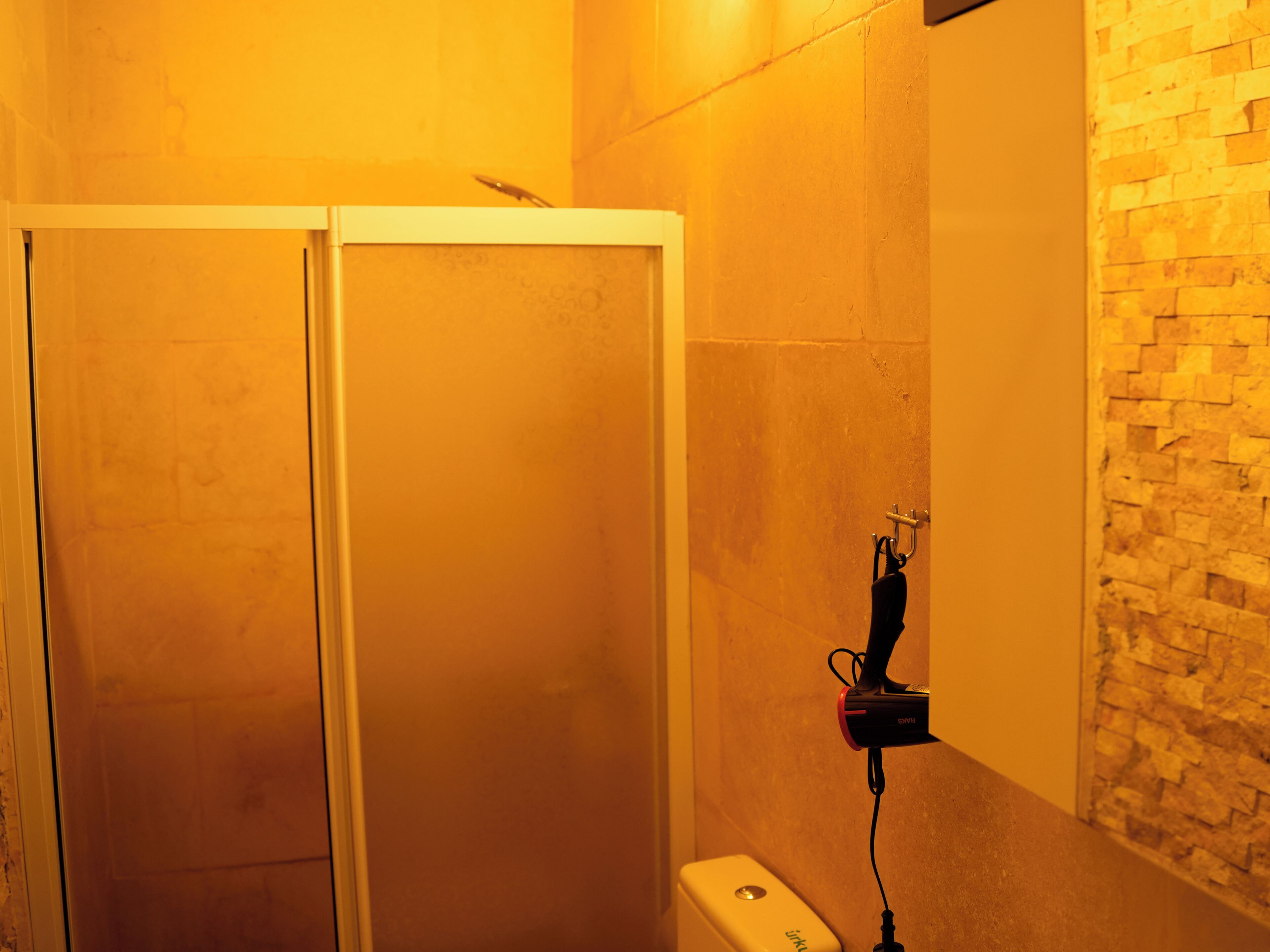 Un baño con cabina de ducha, un perchero y una pared de piedra.