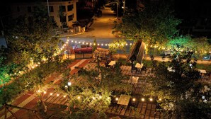 An outdoor seating area with tables and chairs, surrounded by greenery and string lights. - Cappadocia Panda Garden House (Nevsehir)