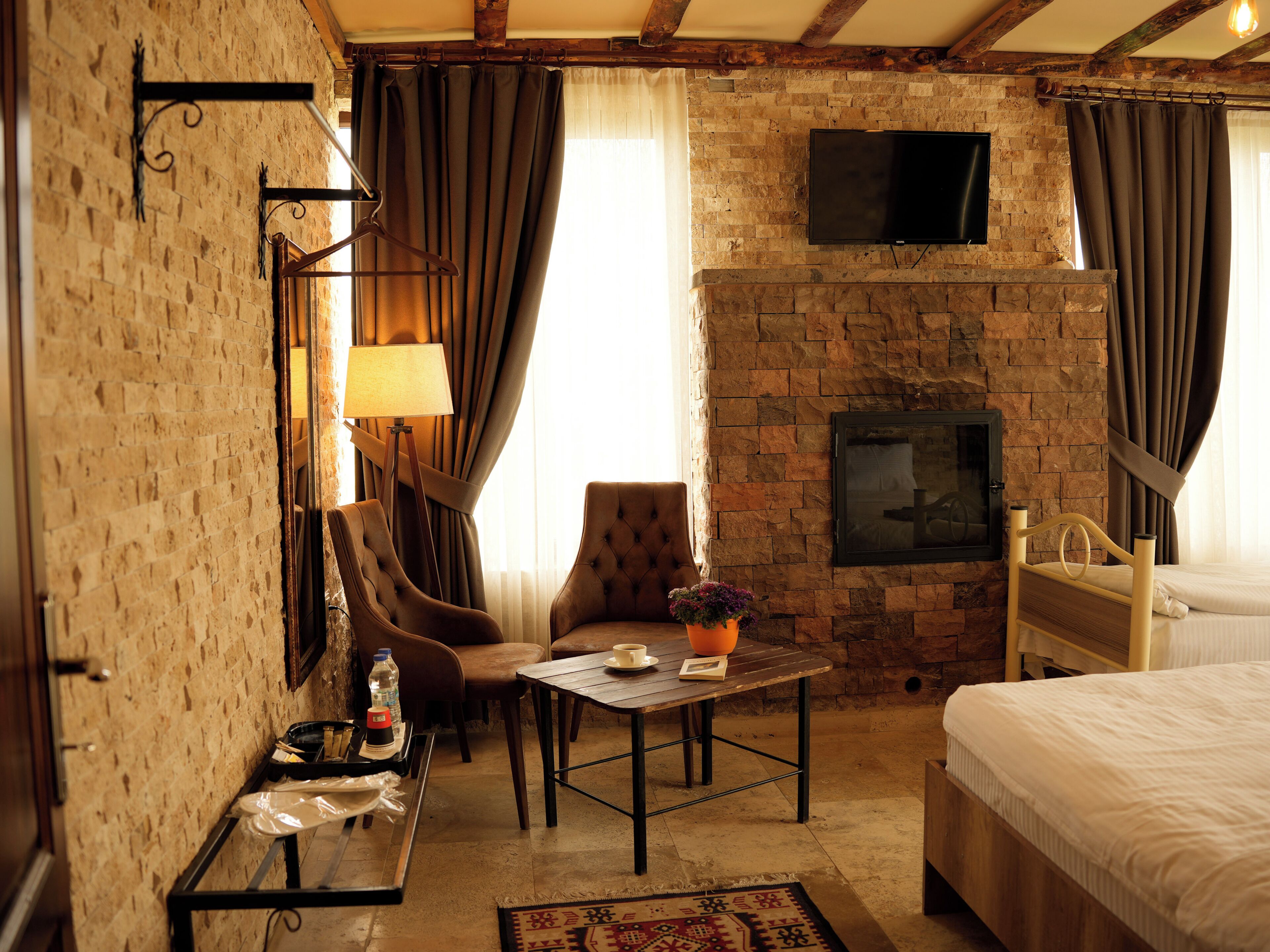 Una habitación con pared de ladrillo, televisor de pantalla plana, cama, mesa con lámpara y una silla.