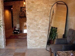 A room with a brick wall, a large mirror, a grey armchair, and a potted plant.