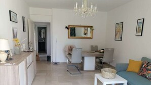 Een moderne woonkamer met een bank, een salontafel, en een eethoek met een stoel en tafel.