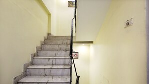 A staircase with marble steps leading upwards, a handrail on the right, and a light fixture above the steps. - OYO Rooms 099 Ram Talai Temple (Amritsar)