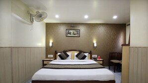 A hotel room with a large bed, two bedside tables, a chair, a desk, a wall-mounted fan, and a painting on the wall. - OYO Rooms 099 Ram Talai Temple (Amritsar)