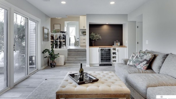 A modern living room with a sofa, a coffee table, and a kitchen area in the background. - Newly Remodeled Home - 20 minutes from anywhere in Omaha! (Omaha)