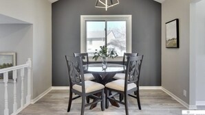 A dining area with a round table, four chairs, and a modern pendant light. - Newly Remodeled Home - 20 minutes from anywhere in Omaha! (Omaha)