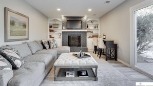 A living room with a fireplace, a sofa, a coffee table, and a bookshelf. - Newly Remodeled Home - 20 minutes from anywhere in Omaha! (Omaha)