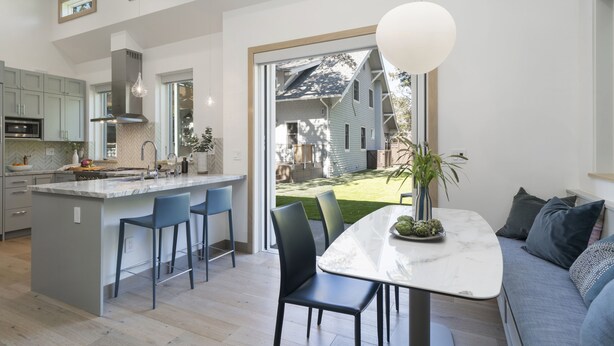 Une cuisine moderne dotée d’un grand îlot central, de tabourets de bar et d’une table à manger avec des chaises.