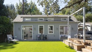 Une maison à deux étages avec un patio couvert, un petit jardin et une cour arrière clôturée.