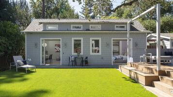 Une maison à deux étages avec un patio couvert, un petit jardin et une cour arrière clôturée.
