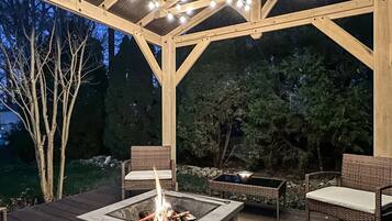 A wooden deck with wicker furniture and a fire pit.