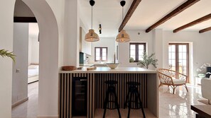 Une cuisine moderne dotée d’un îlot central, de luminaires suspendus et d’un coin repas avec une chaise.