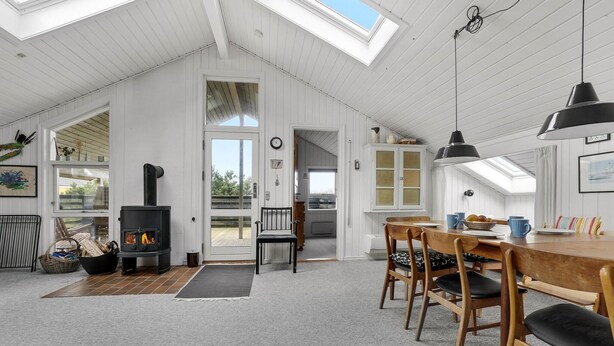 A cozy, well-lit room with a fireplace, wooden furniture, and a view through a glass door. - Amazing home in Thisted with sauna (Thisted)