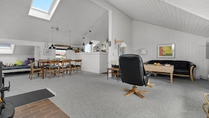 A spacious loft with a high ceiling, a dining area, a black leather chair, and a kitchen area. - Amazing home in Thisted with sauna (Thisted)