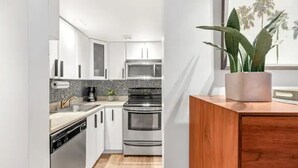 Una cucina moderna con mobili bianchi, piano cottura in acciaio inossidabile e forno a microonde.
