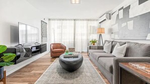 Un soggiorno moderno con un divano, un tavolino, una TV e una parete decorativa.