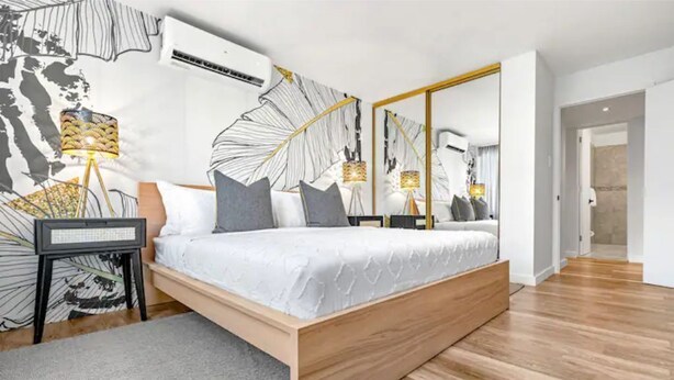 Una camera da letto moderna con un letto di legno, un grande specchio e un condizionatore d'aria a parete.
