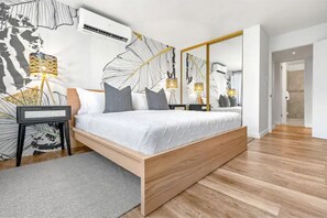 Un dormitorio moderno con una cama de madera, un espejo grande y un aire acondicionado de pared.