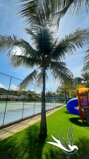 Surrounded by lush greenery, this serene outdoor space offers a sports court and a playground for families to enjoy.